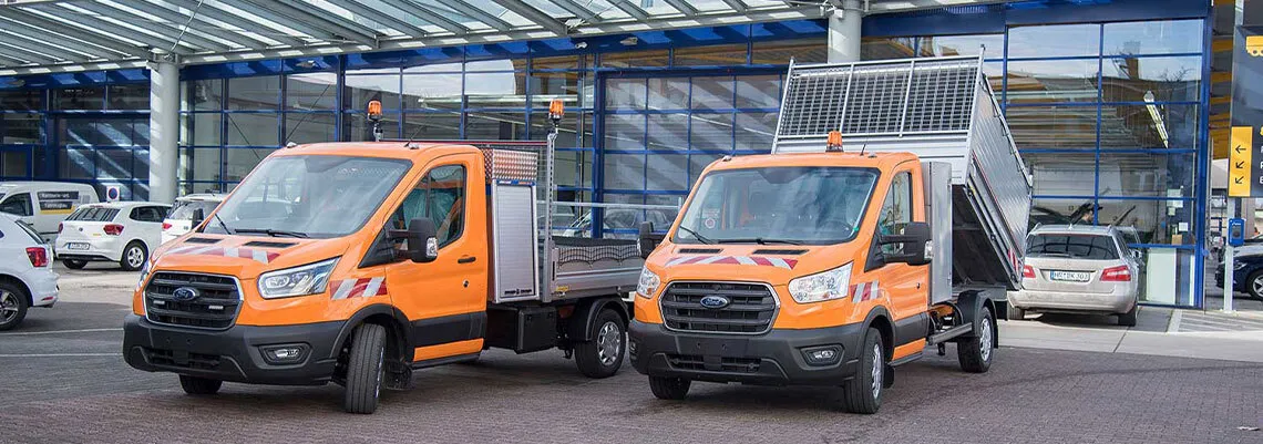 Bild zeigt zwei Fahrzeuge der Städtischen Verwaltung, des Bauhofs oder Gartenbauamt, einer mit offener Ladefläche und Boxen zum Verstauen von Geräten und einer mit kippbarer Ladefläche und Gitterkastenaufbau